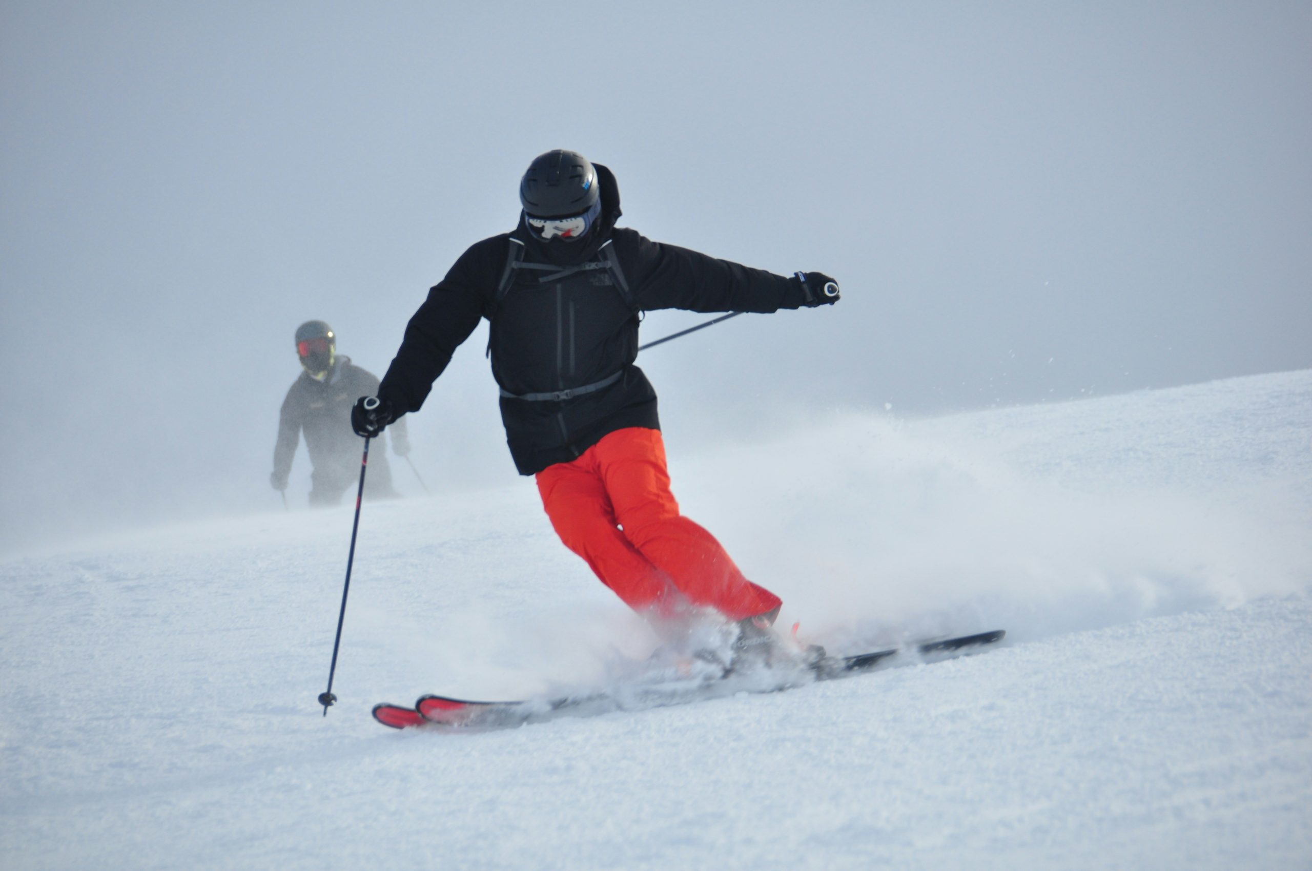 Person med skidutrustning på snötäckt bergssluttning under blå himmel