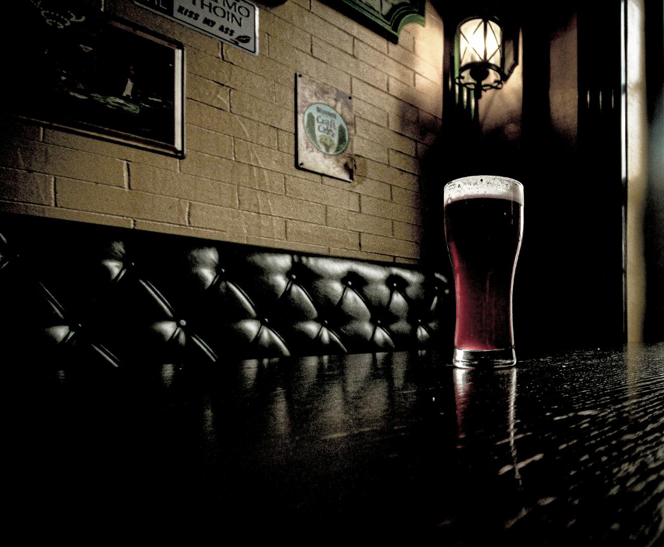 Bartender tappar upp öl från en blank kran i ett glas bakom en bar