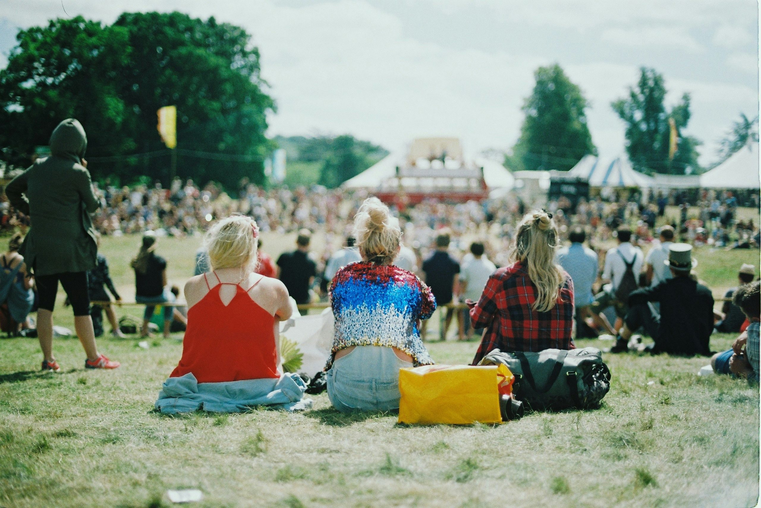 Upplyst festivalscen på kvällen med färgade strålkastare, rök, stor videoskärm och publik framför på Roskilde Festival.