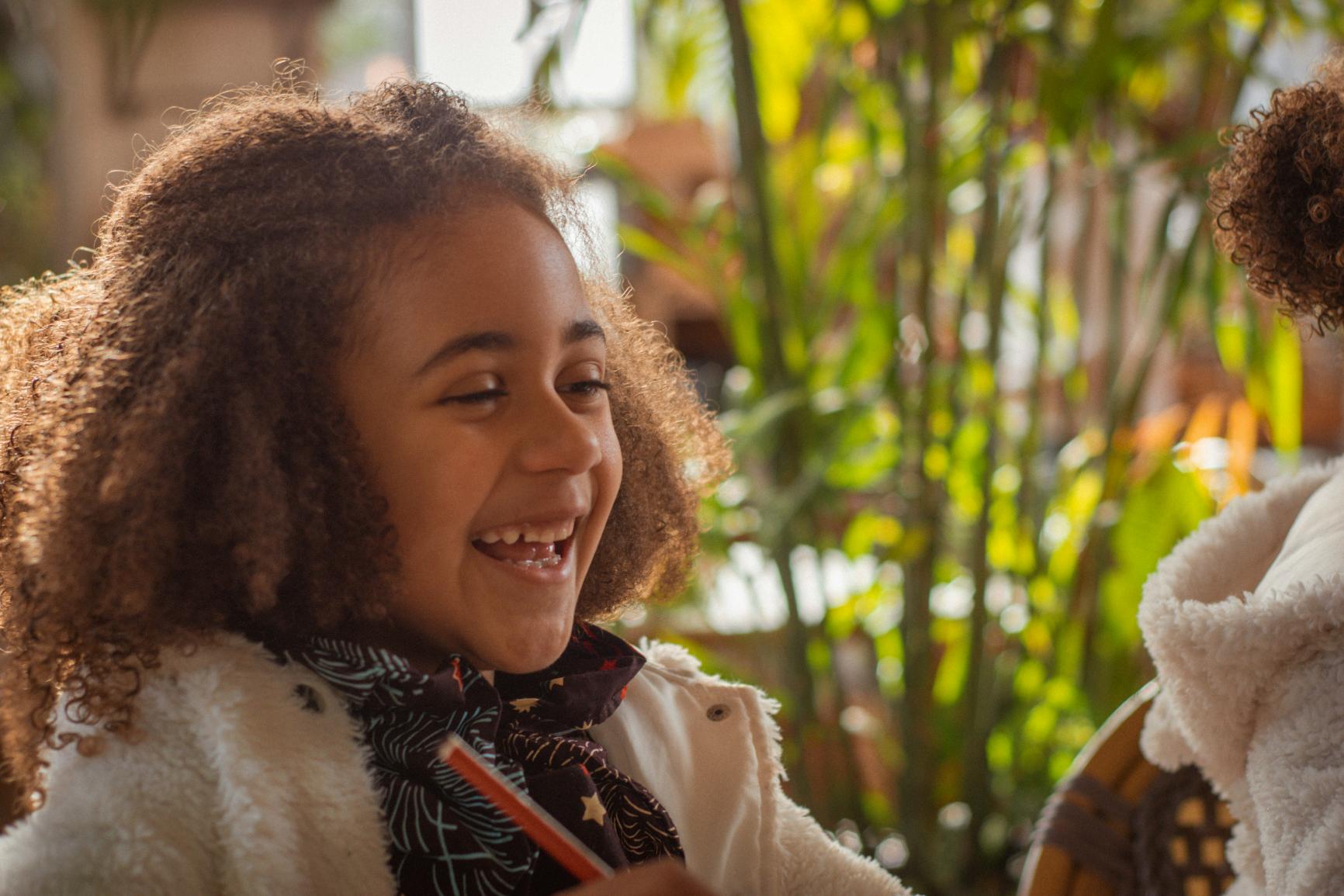 Skrattande barn med penna inomhus, redo för kluriga gåtor i quizet Runda 1